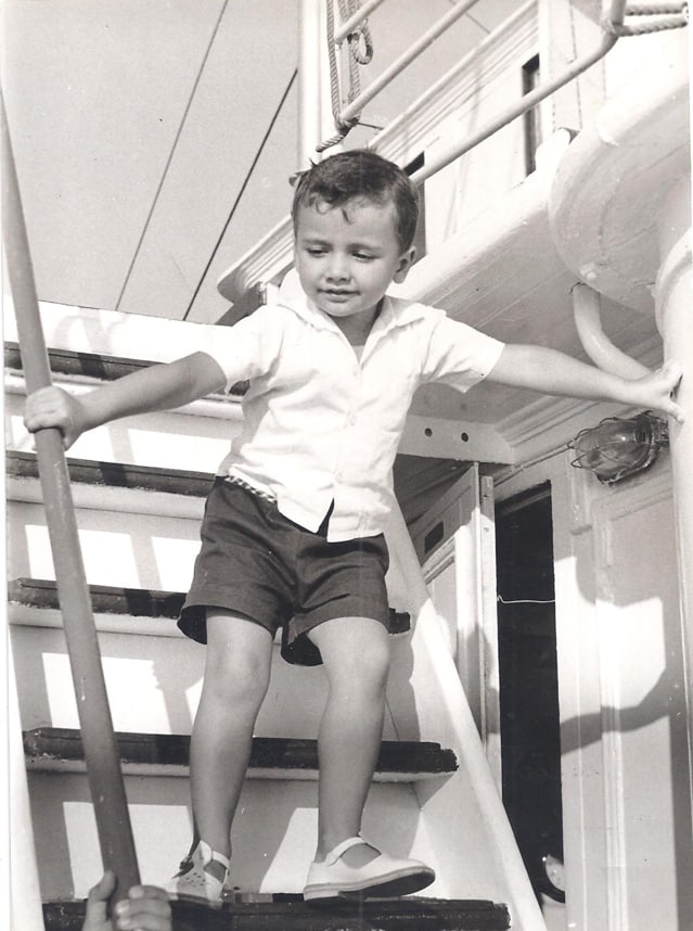 Yiannis Vogiatzoglou as a boy, standing on a ship's companionway
