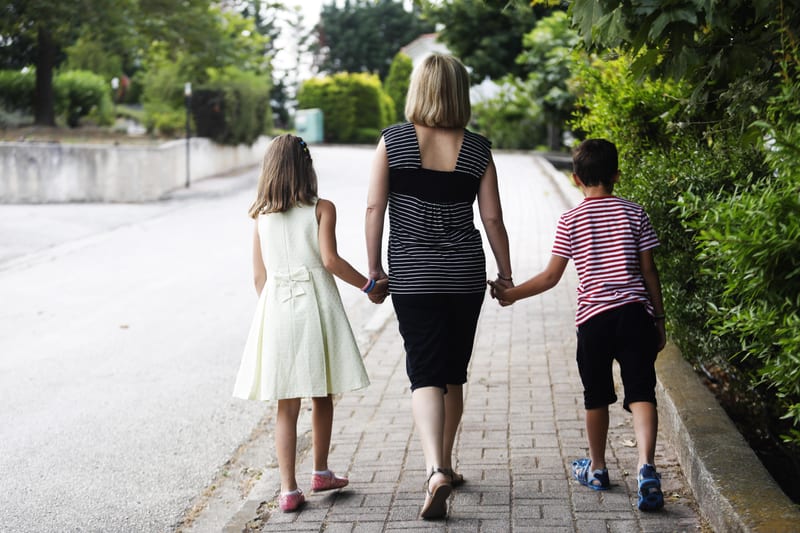 A mother and two children walking home hand in hand